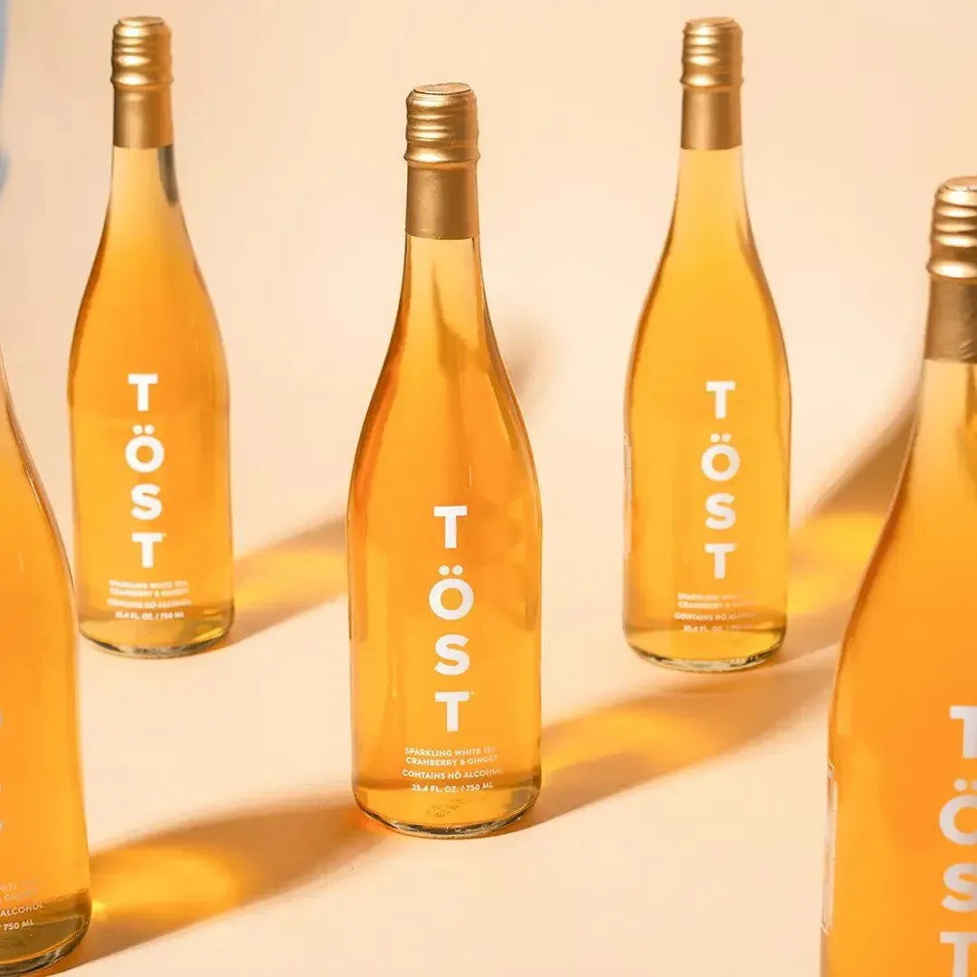 TÖST espumante sin alcohol servido en copa — alternativa champagne té blanco y arándano